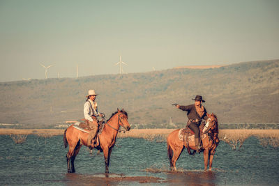 Men riding horses at lake