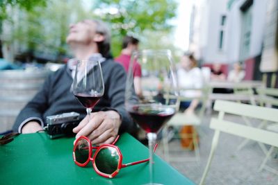 Mature man having red wine while sitting at outdoor restaurant