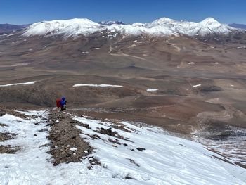 Rear view of man walking on snow covered mountain