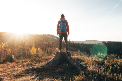 Active hiker standing on a stump enjoys the feeling of reaching the top of the mountain at sunrise