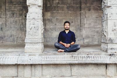 Man doing yoga against wall