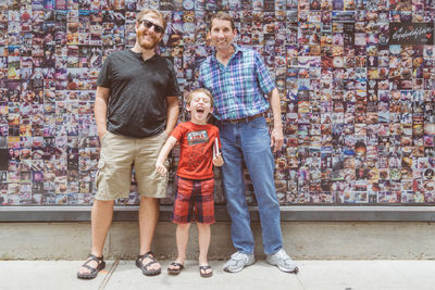 Full length of father with daughter standing against wall