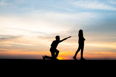 Silhouette man and woman against sky during sunset