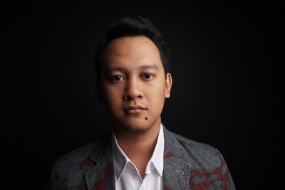 Portrait of young man against black background