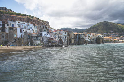 Buildings by sea against sky in town