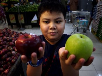 High angle view of boy holding apples while standing in supermarket