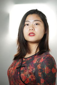 Portrait of young woman standing against white background