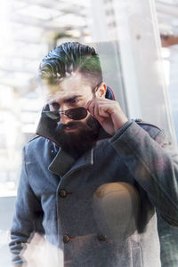 Side view of young man looking through window