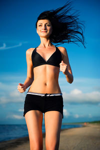 Portrait of smiling young woman standing at beach