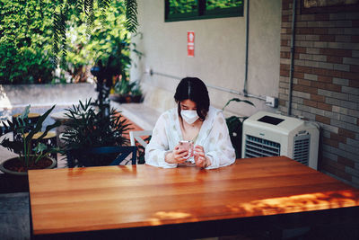 Rear view of woman sitting on table