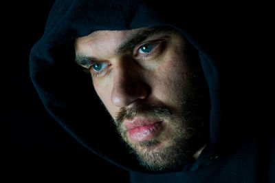 Close-up portrait of mid adult man against black background