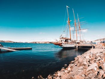 Sailboats moored on sea against blue sky