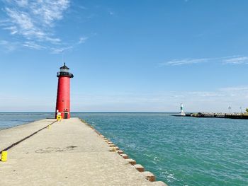 Lighthouse by sea against sky