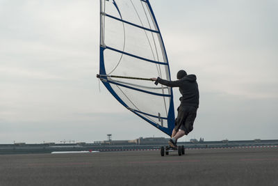 Rear view of man windsurfing on runway