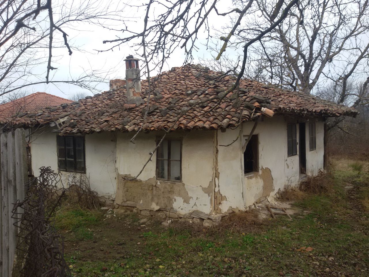 ABANDONED HOUSE AGAINST BARE TREES