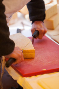 Midsection of man cutting cheese on table