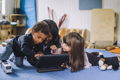 Female teacher sharing digital tablet with children in child care center