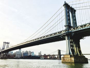 Manhattan bridge over east river against sky in city