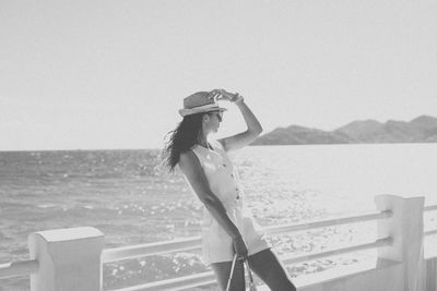 Side view of woman standing against sea