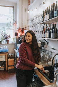 Smiling female cafe owner washing dishes in coffee shop