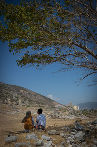 Rear view of woman sitting on rock