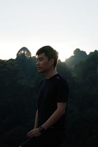 Young man looking away against mountains