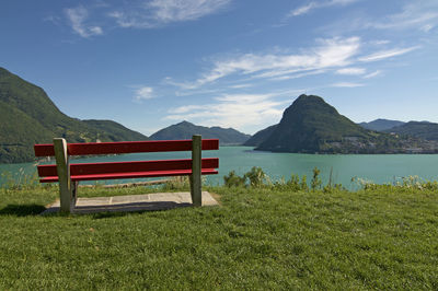 Empty bench by plants against sky