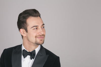 Portrait of young man looking away against white background
