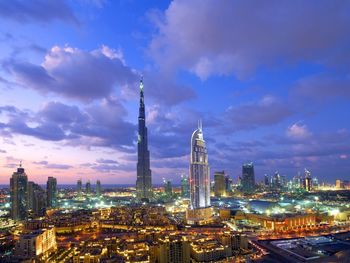 Burj khalifa in illuminated city against sky