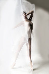 Full length of ballet dancer dancing against white background