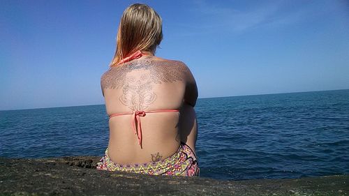 Woman standing by sea against sky