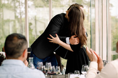 Rear view of friends sitting on table at restaurant