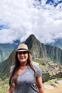 Portrait of smiling young woman standing against mountains