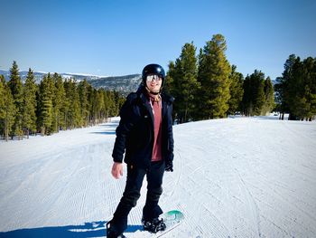 Portrait of a young man snowboarding, standing on a beautiful mountain slope.