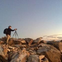 Man photographing on mountain against clear sky