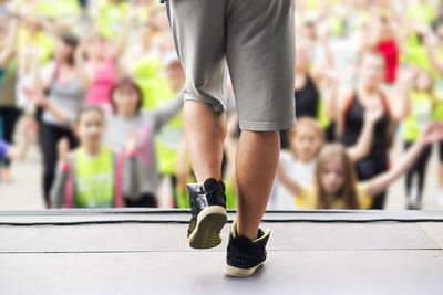 Low section of person exercising on stage with people in background