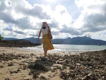 Woman standing on beach against sky