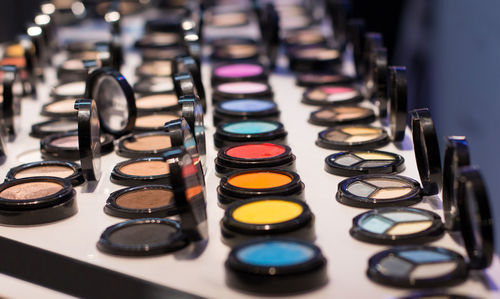 Different colors of eye shadow on the shop window in the cosmetic store.