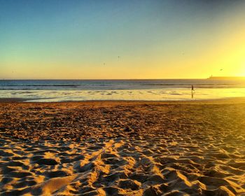 Scenic view of beach against clear sky during sunset