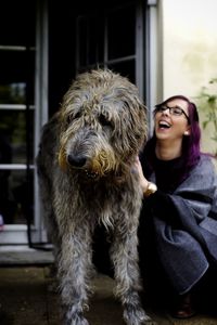 Woman laughing while stroking irish wolfhound on porch