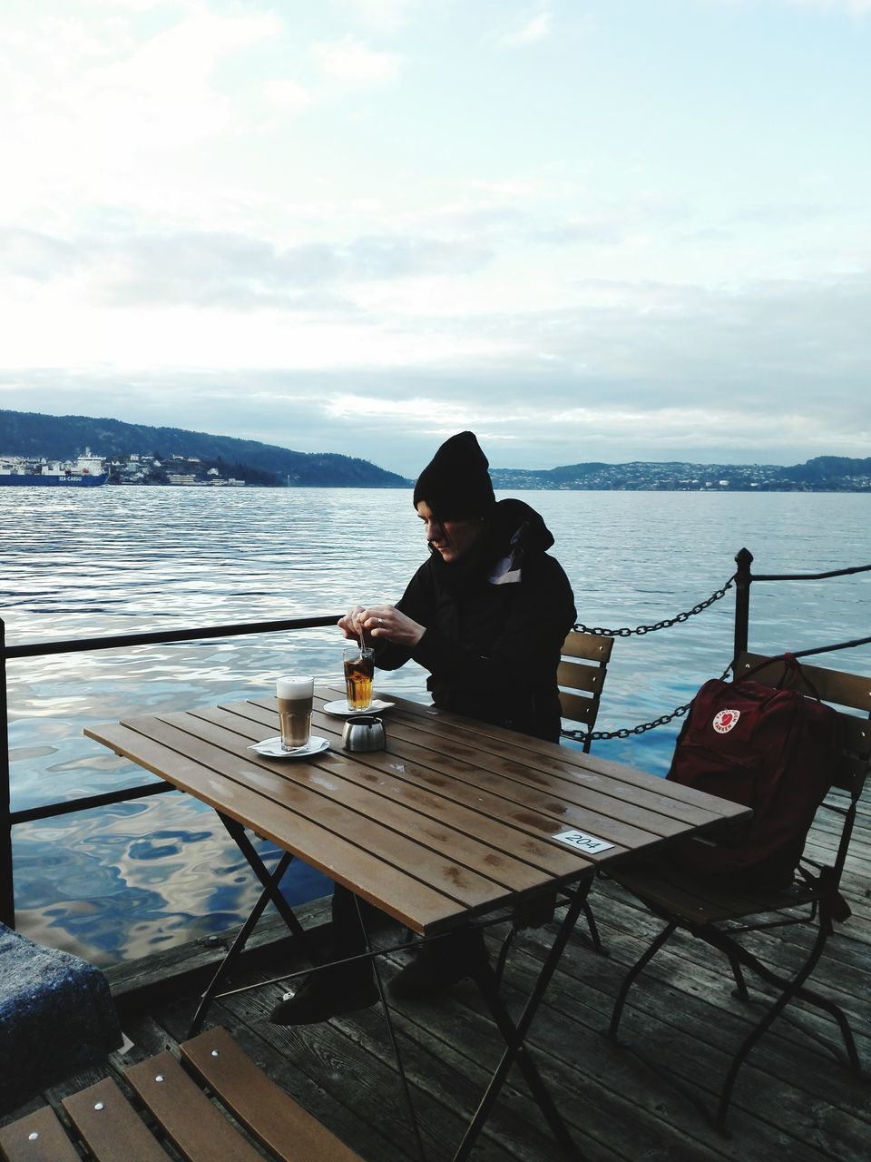 water, sitting, lifestyles, leisure activity, sky, relaxation, rear view, nautical vessel, casual clothing, sea, young adult, lake, waist up, pier, boat, tranquility, transportation, full length