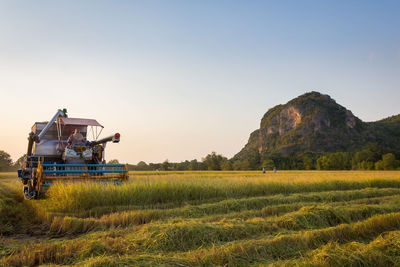 Combine harvester working on agricultural field against sky