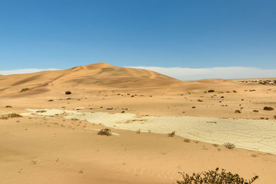 Scenic view of desert against clear blue sky