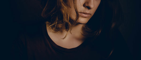 Close-up of young woman against black background