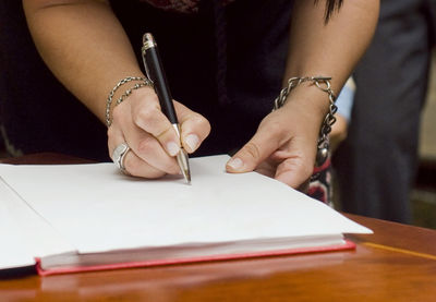 Midsection of woman reading book on table