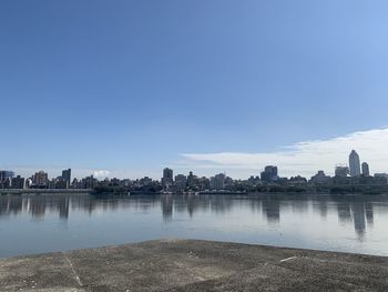 River by buildings against blue sky