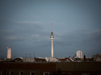 View of communications tower in city against sky