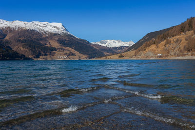 Scenic view of sea and mountains against clear blue sky