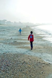 Rear view of people walking on beach