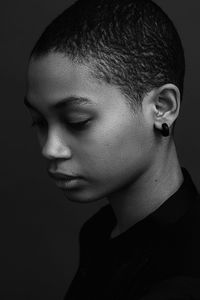 Close-up of thoughtful woman against black background